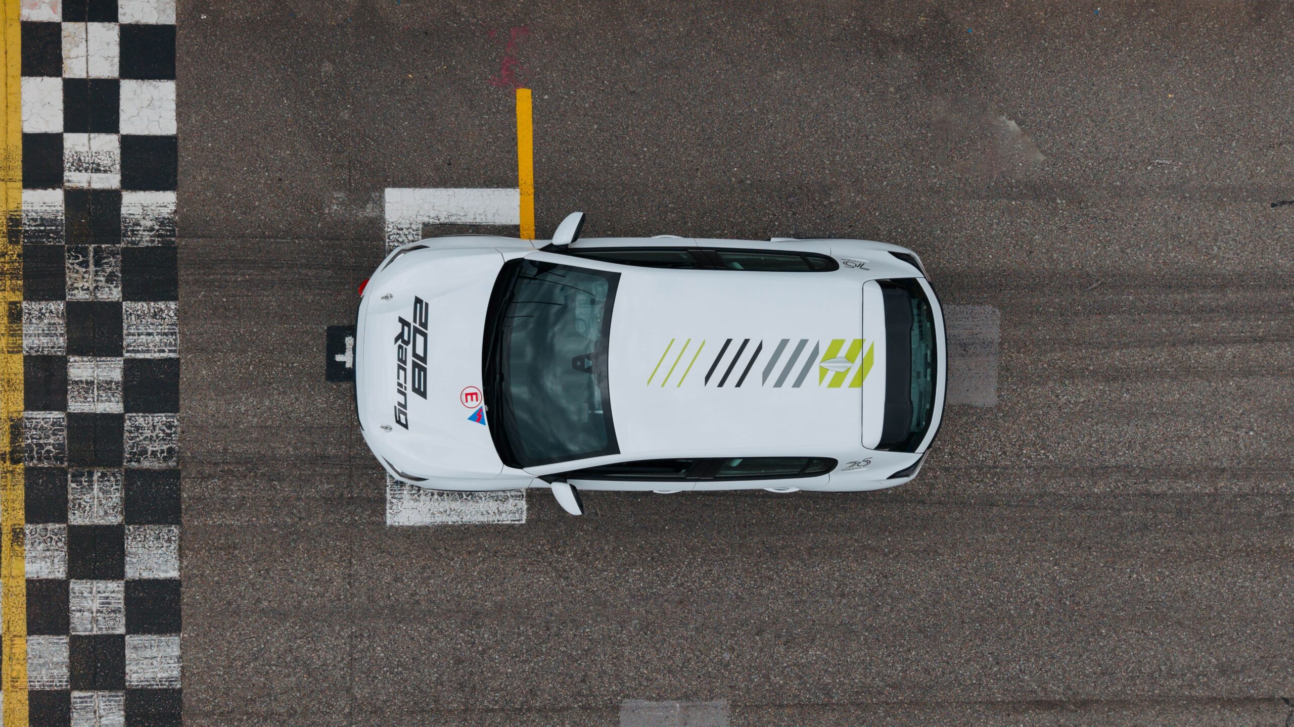 An overhead photo of a Peugeot 208 Racing TC6 on the starting grid of a racetrack.