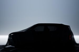 Side on view of a Kia EV2 under covers.