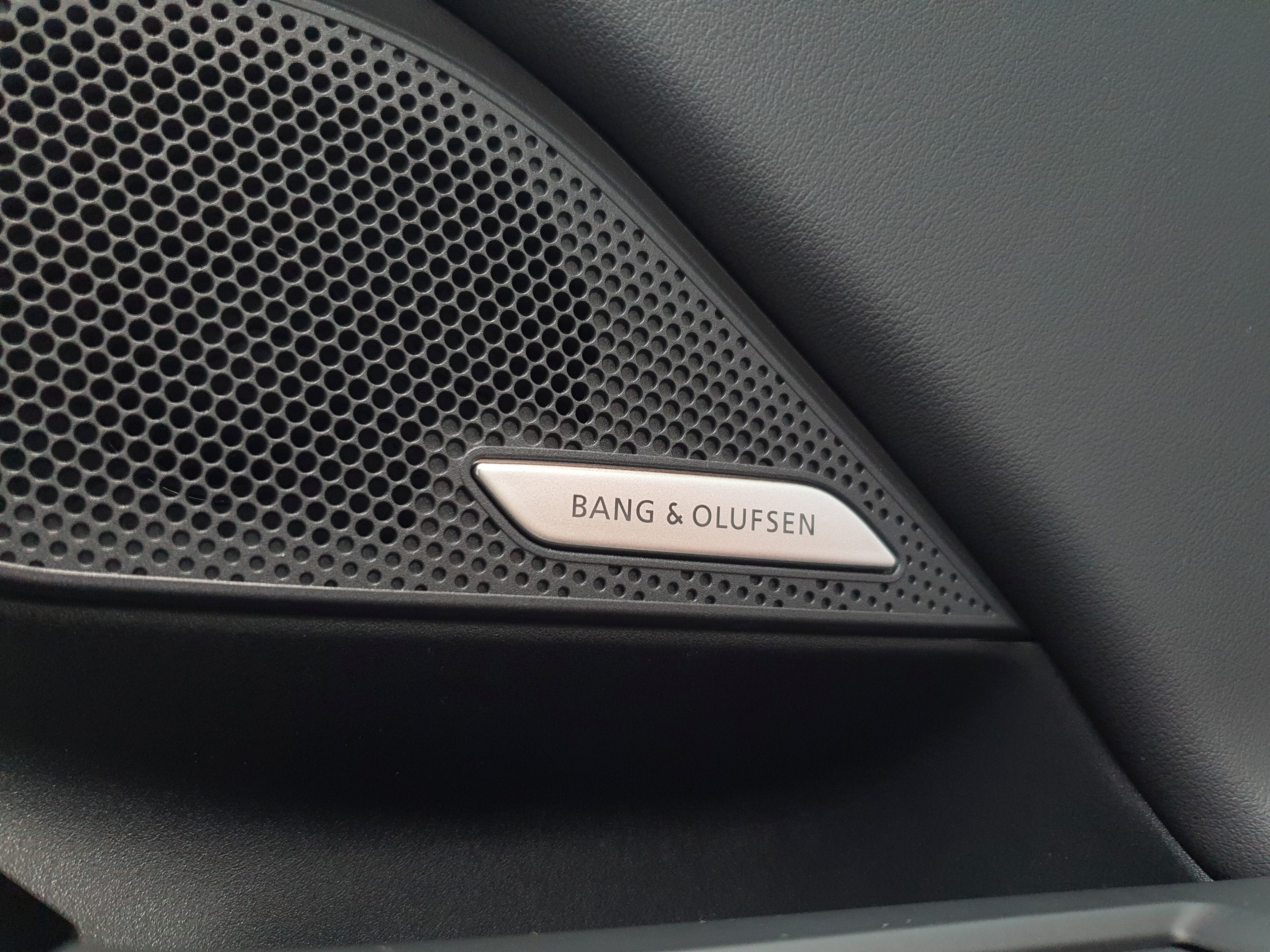 Bang and Olufsen badging on the speaker housing on the interior of an Audi A6 Avant e-tron S-Line quattro in Siam Beige.
