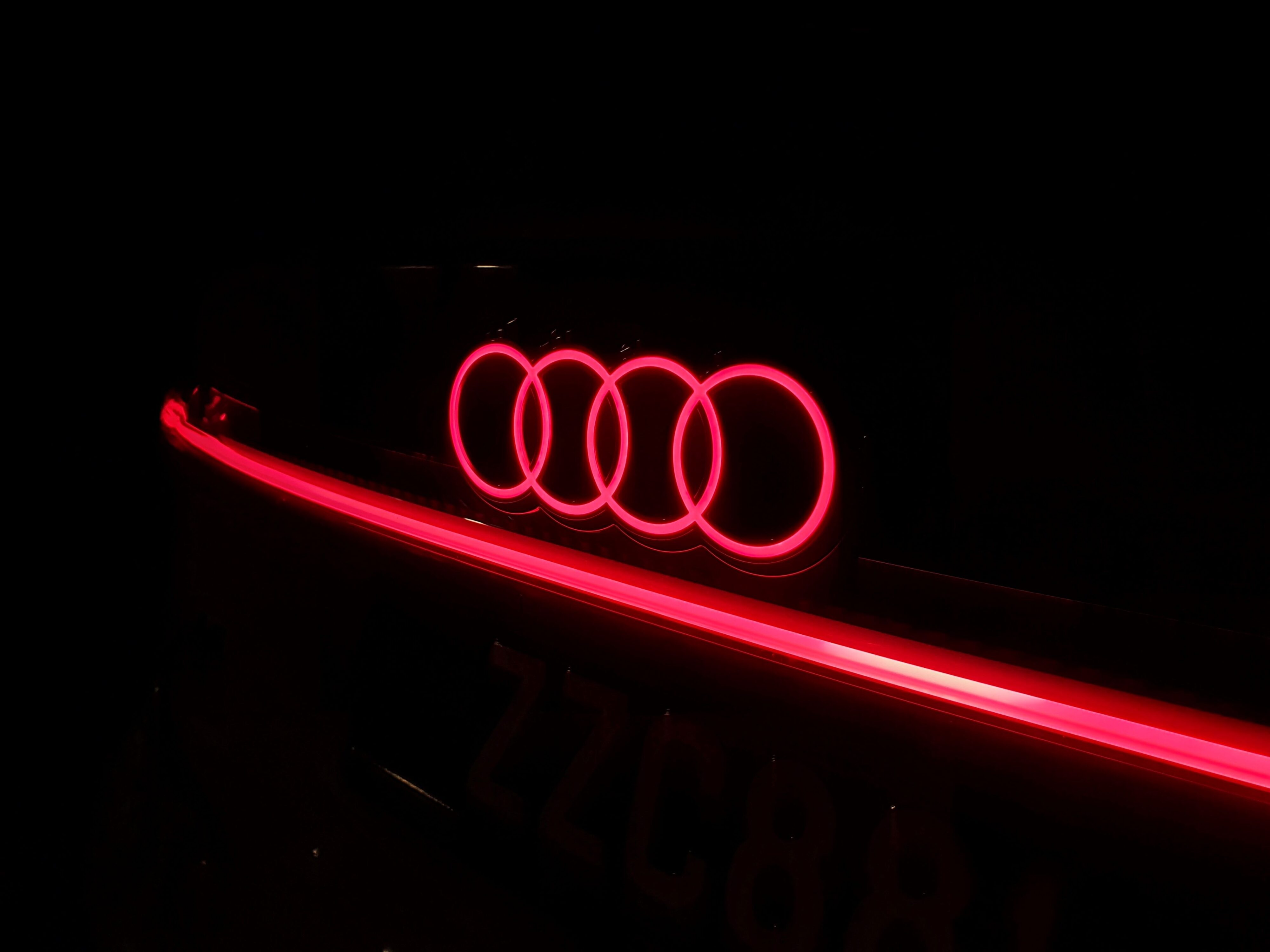Illuminated Audi logo and light bar on the rear of an Audi A6 Avant e-tron S-Line quattro in Siam Beige.