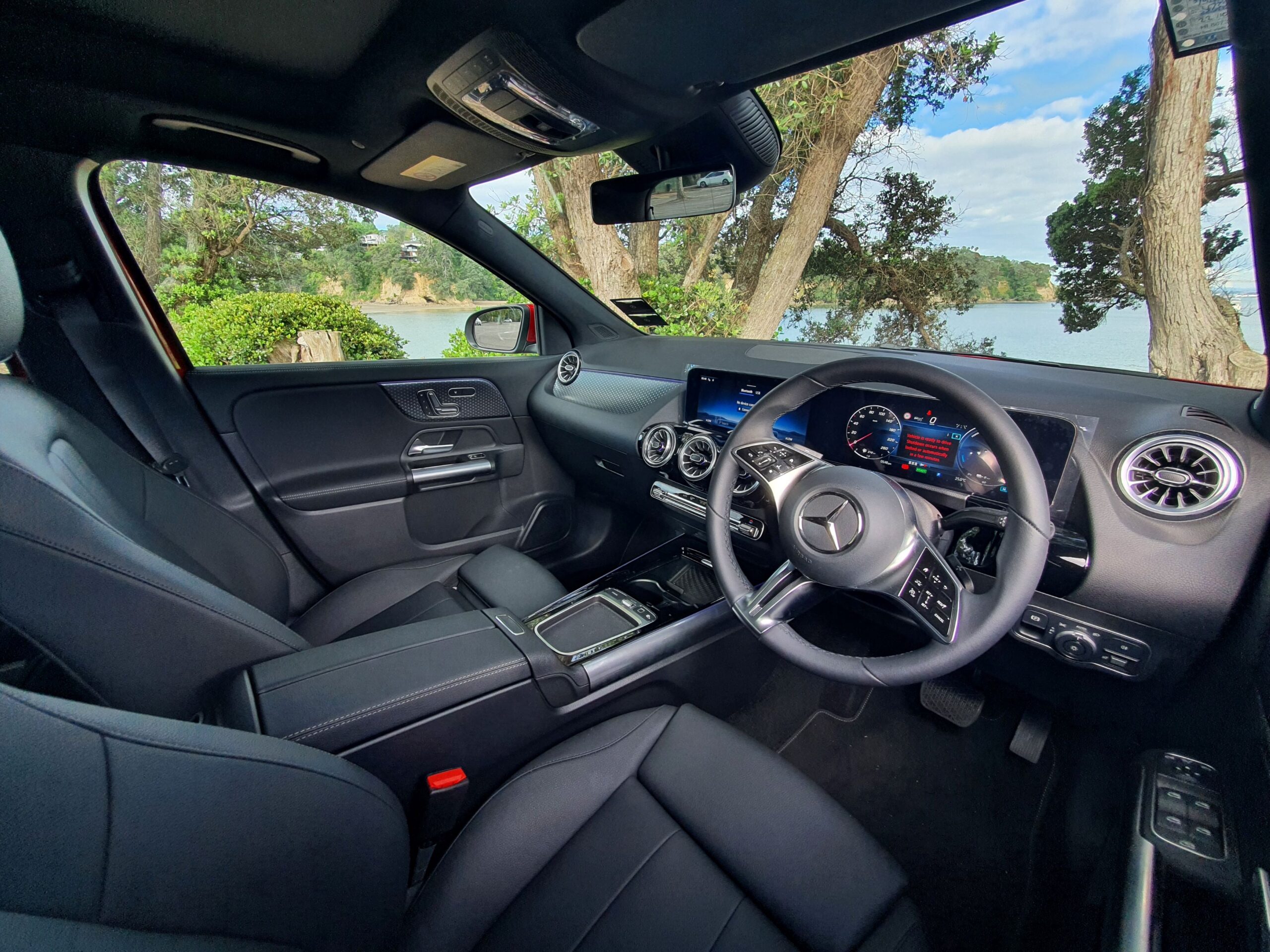 Interior view of a 2025 Mercedes-Benz GLA250e in Patagonia Red Metallic with the ocean in the background.