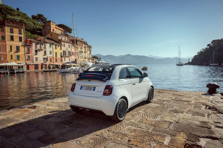 Rear three quarters view of a Fiat 500 Dolcevita Special Series in white with an Italian town and the ocean in the background.