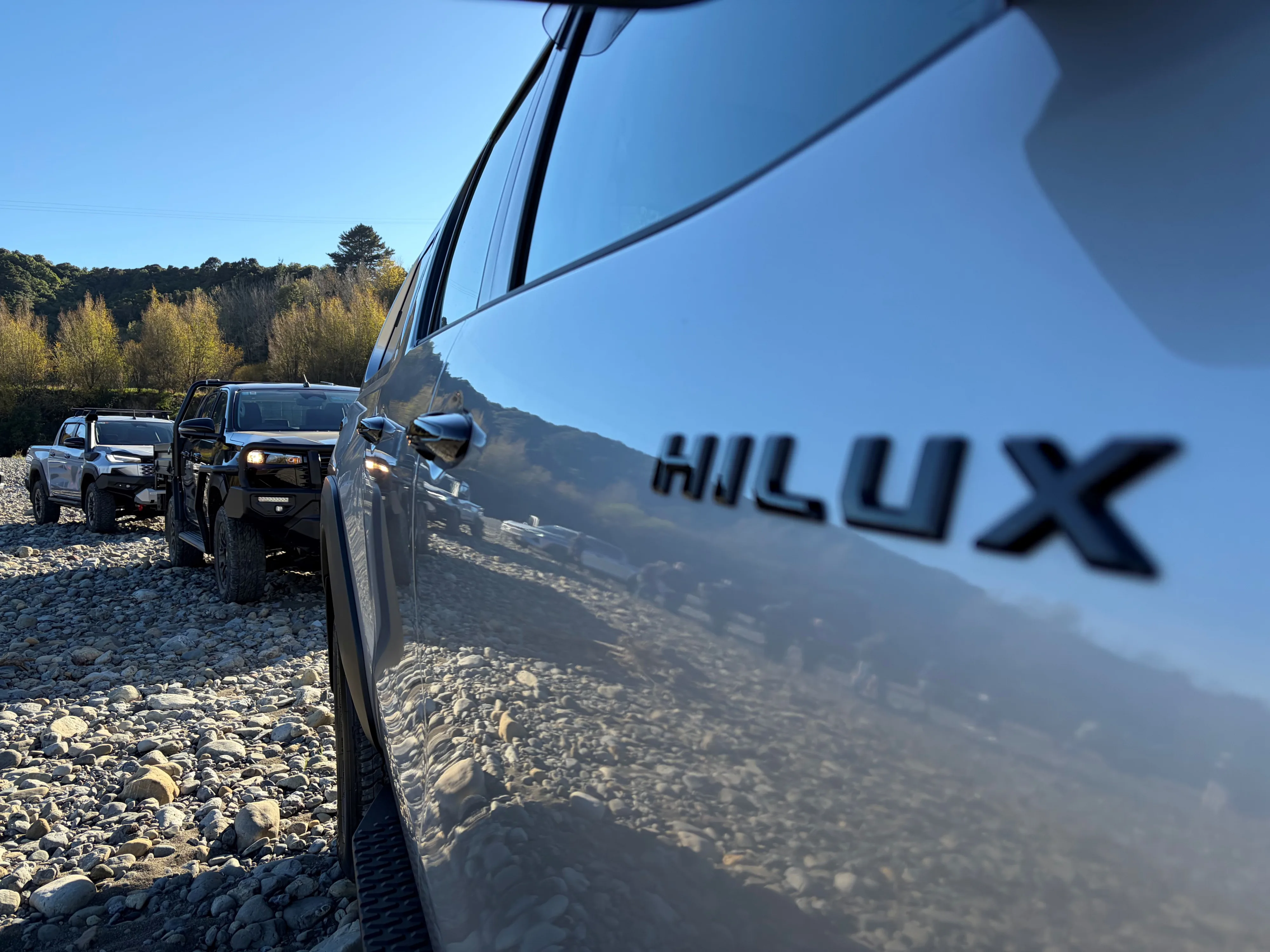 Close up of the Hilux badge on the side of a 2026 Toyota Hilux with two 2026 Hiluxes in the background, taken on the 2026 New Zealand launch of the ninth-generation Hilux in Manawatu, New Zealand.