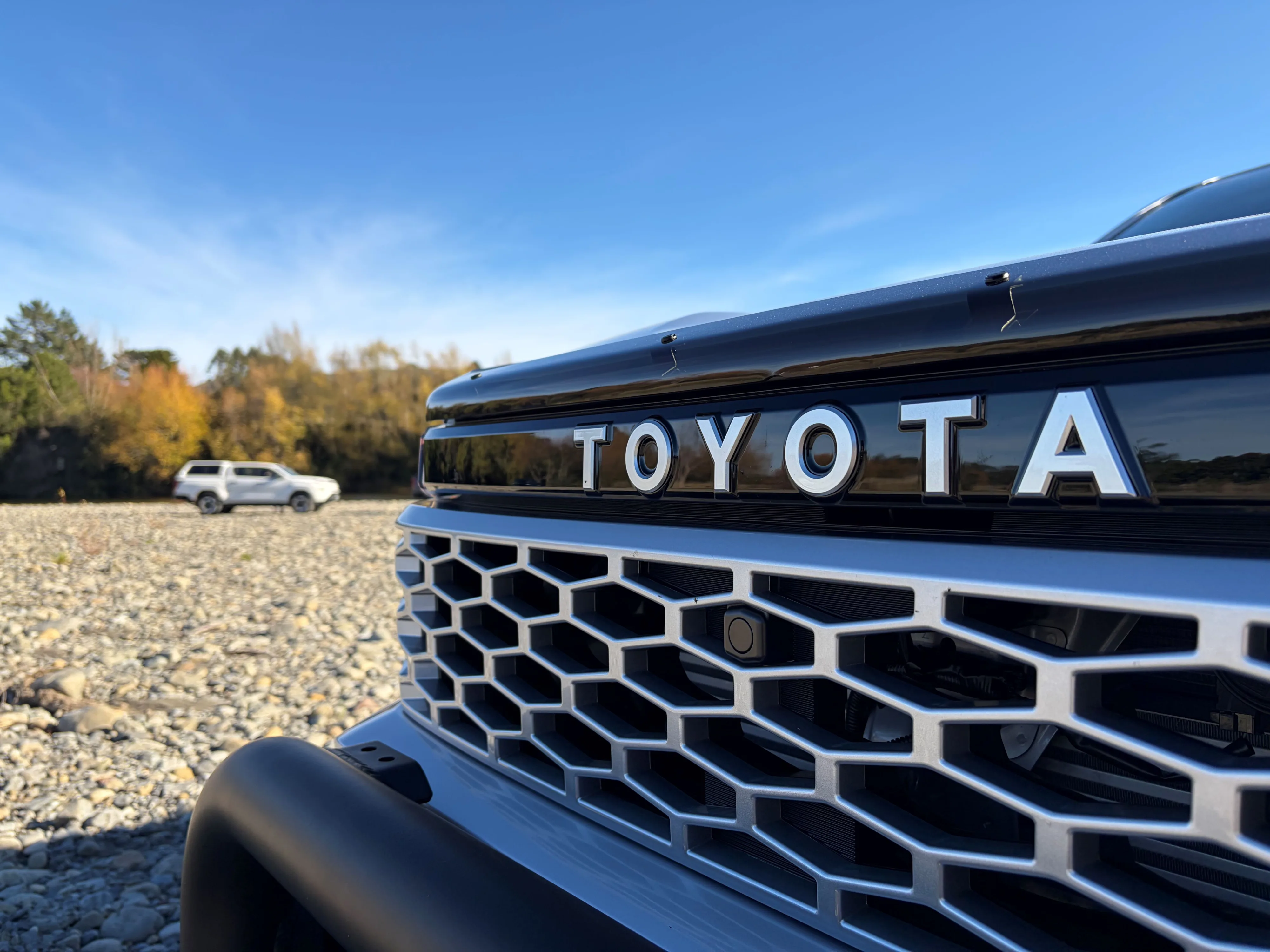 Close up of the Toyota badge on the nose of a 2026 Toyota Hilux with another 2026 Hilux in the background, taken on the 2026 New Zealand launch of the ninth-generation Hilux in Manawatu, New Zealand.