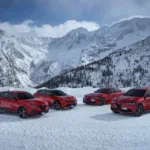 A photo of Alfa Romeo's current lineup atop a snow covered mountain. From left, Tonale, Junior, Giulia and Stelvio, all in Rosso Alfa (red).