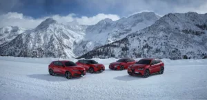 A photo of Alfa Romeo's current lineup atop a snow covered mountain. From left, Tonale, Junior, Giulia and Stelvio, all in Rosso Alfa (red).