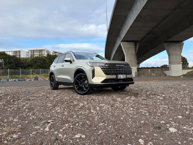 Front three quarters view of a 2026 GWM Haval H6 HEV in Astral Pearl, photographed against an urban backdrop.