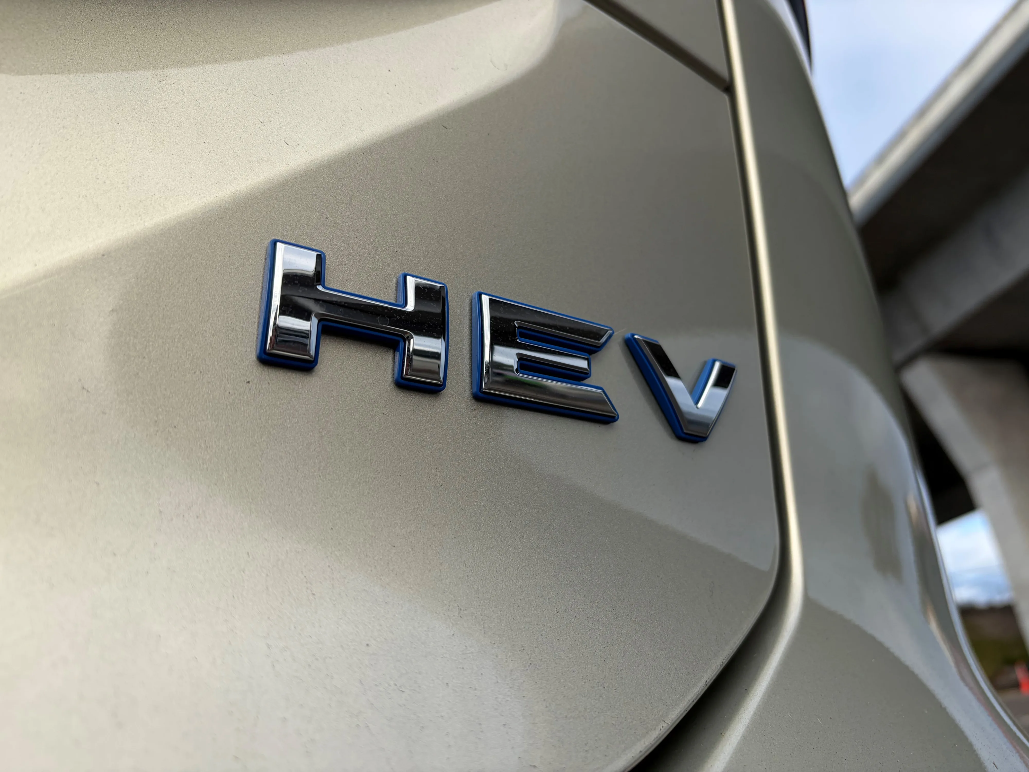 Close-up of the HEV badge on the rear of a 2026 GWM Haval H6 in Astral Pearl.