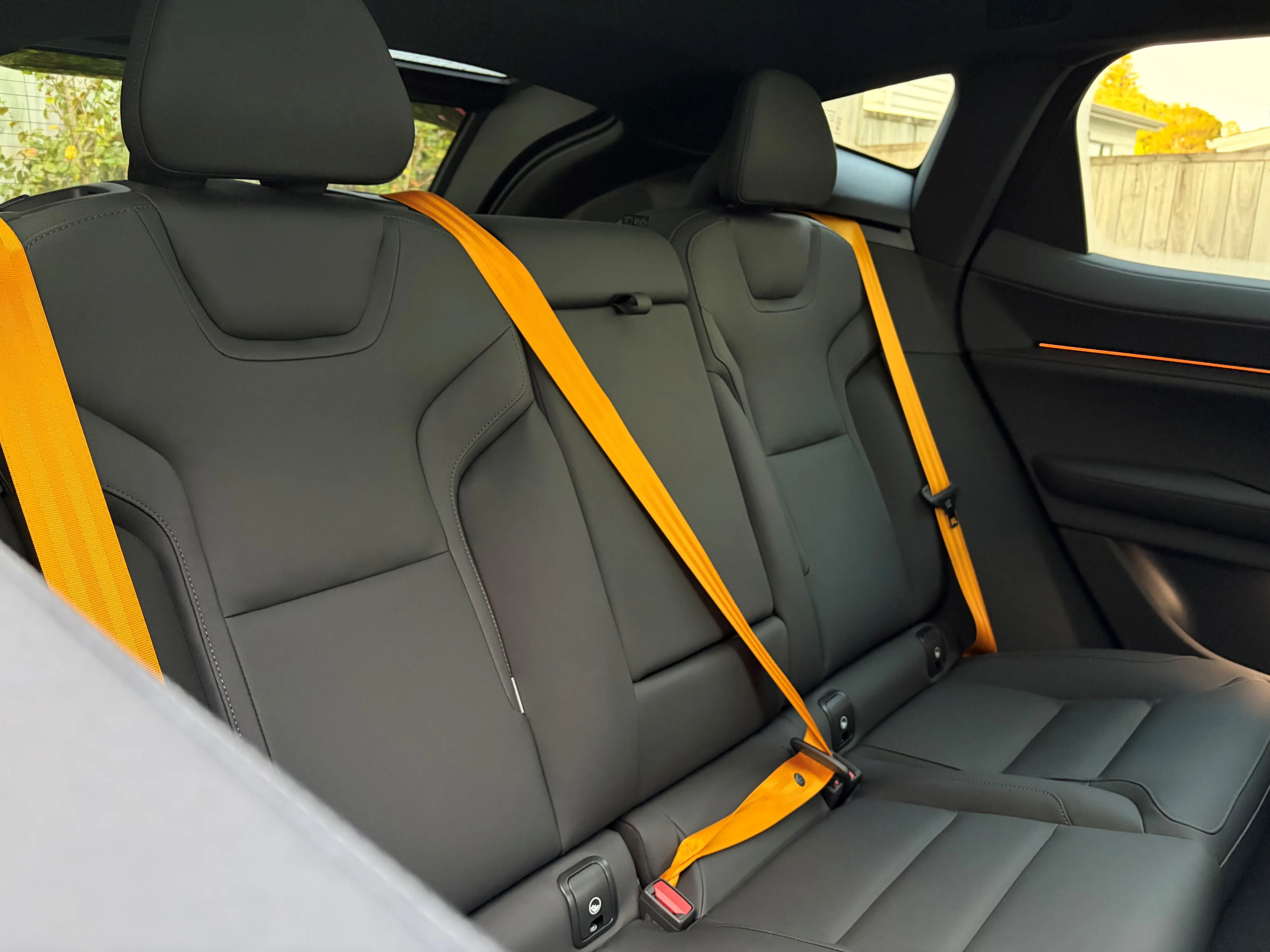 Photo of the backseats of a 2026 Polestar 3 Performance with the 'Swedish Gold' seatbelts clipped in place.