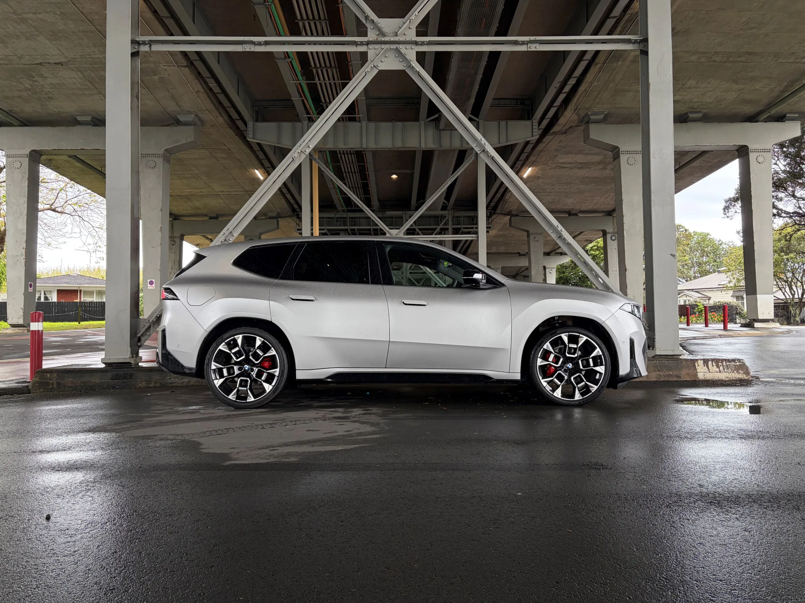 Side on view of a 2026 BMW iX3 50 in Frozen Space Silver metallic, picture taken under Auckland's Harbour Bridge.