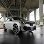 Front three quarters view of a 2026 BMW iX3 50 in Frozen Space Silver metallic, picture taken under Auckland's Harbour Bridge.