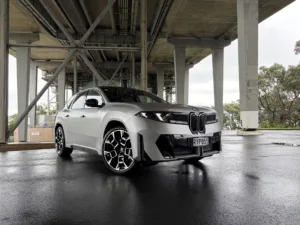 Front three quarters view of a 2026 BMW iX3 50 in Frozen Space Silver metallic, picture taken under Auckland's Harbour Bridge.