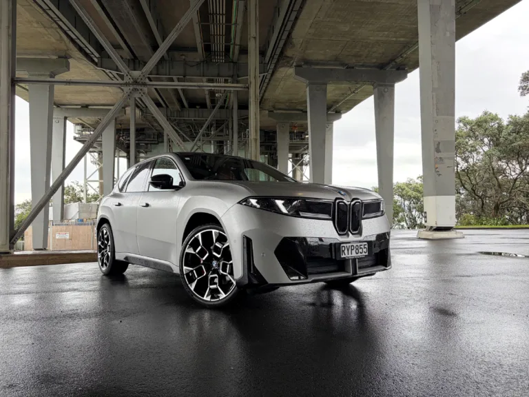 Front three quarters view of a 2026 BMW iX3 50 in Frozen Space Silver metallic, picture taken under Auckland's Harbour Bridge.