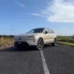 Front three quarters view of a 2026 Volvo EX90 Ultra Twin Motor Performance in Sand Dune with a natural background.