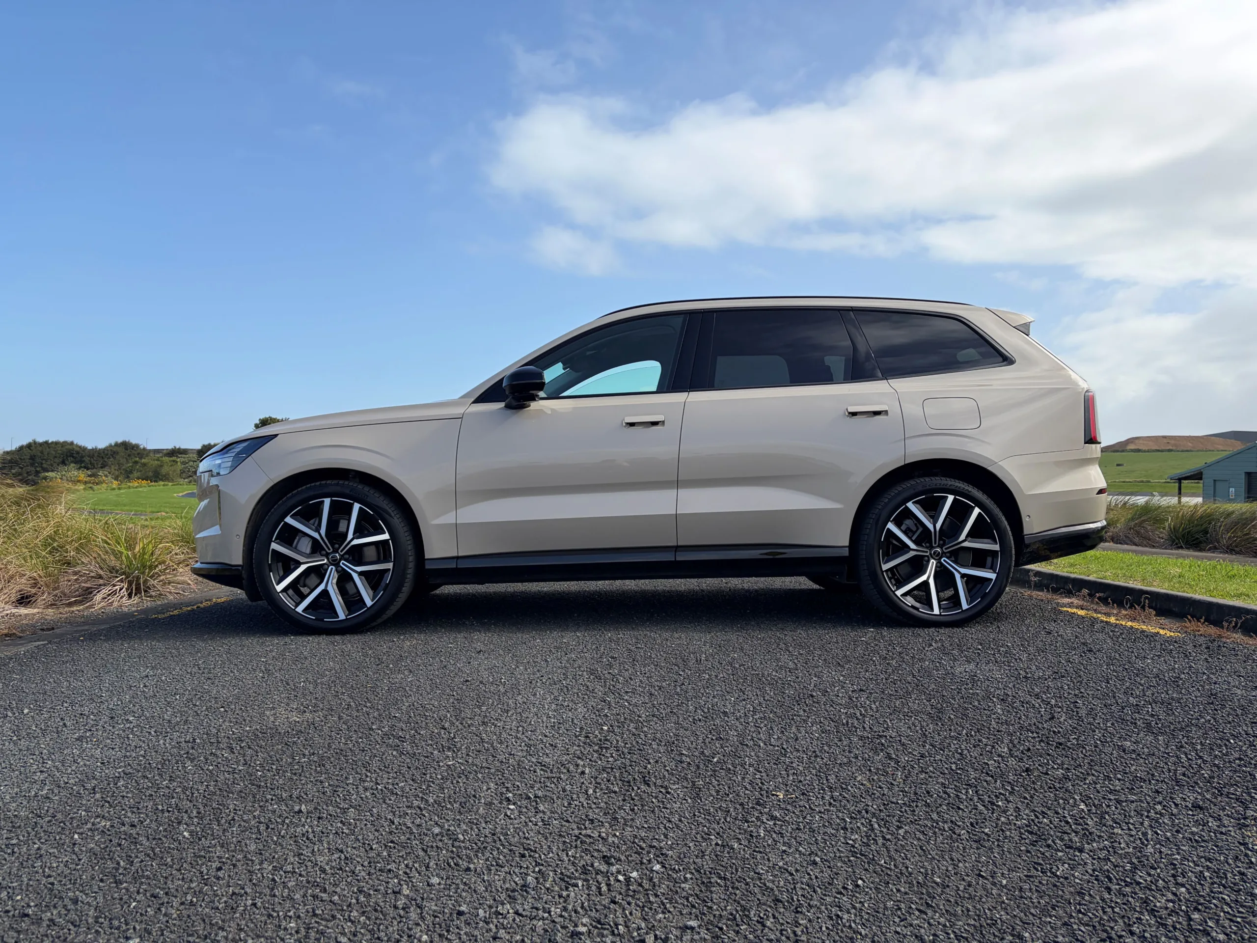 Side on view of a 2026 Volvo EX90 Ultra Twin Motor Performance in Sand Dune with a natural background.